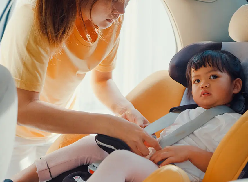mãe colocando filha na cadeirinha com seguro auto
